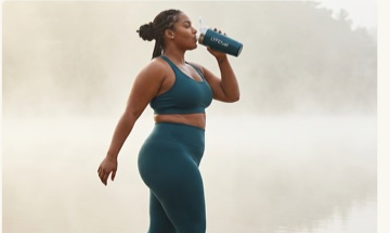 Athlete walking by a lake drinking from a LyfeFuel shaker